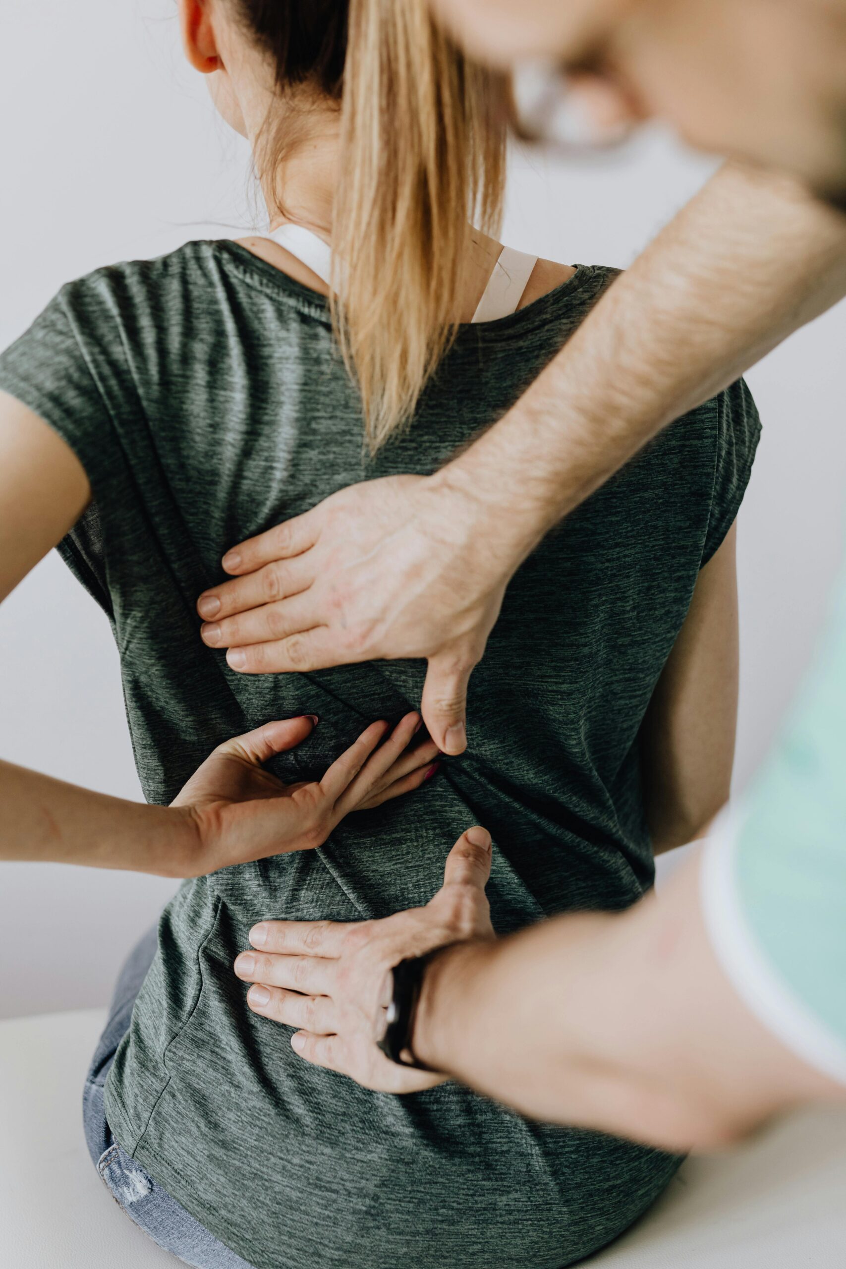 femme assis sur table consultation, un kine masse le dos